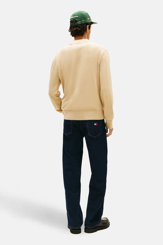 Beige trui van TOMMY JEANS, met lange mouwen, gecombineerd met donkere jeans en zwarte schoenen, gezien vanaf de achterkant.