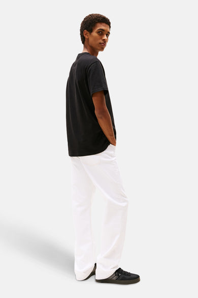 Zwart T-shirt met korte mouwen van TOMMY JEANS, met een ronde hals en gedragen met een witte broek.
