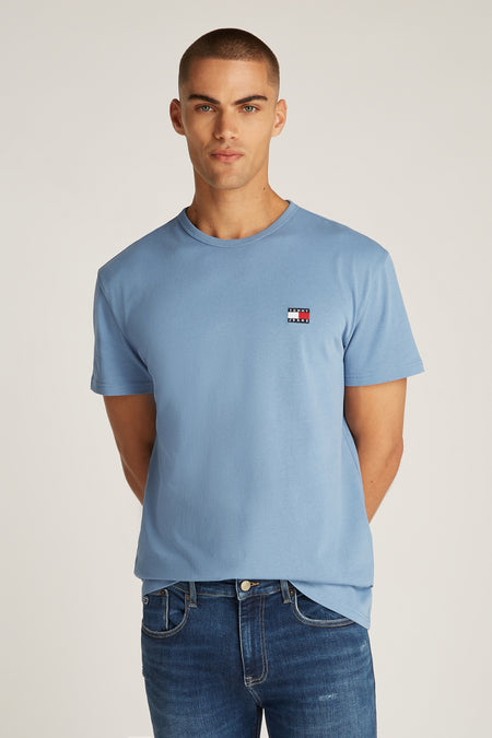 T-shirt bleu à manches courtes de TOMMY JEANS, avec logo sur la poitrine et porté avec un jean brut foncé.
