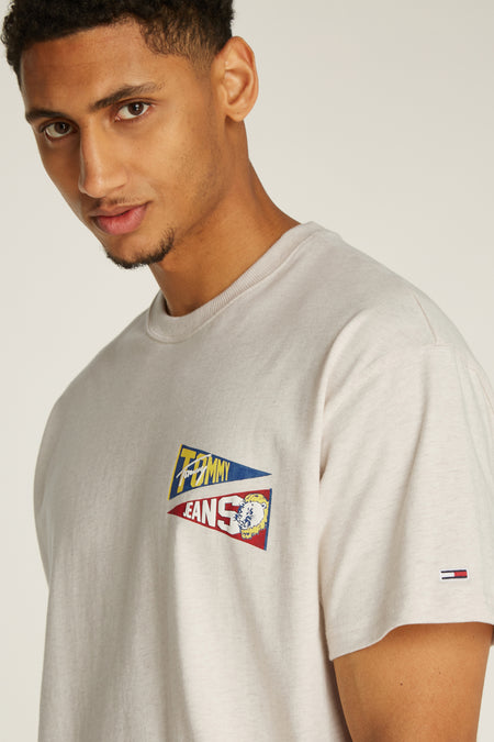 T-shirt écru à manches courtes de Tommy Jeans, avec une impression graphique sur la poitrine et un logo sur la manche.