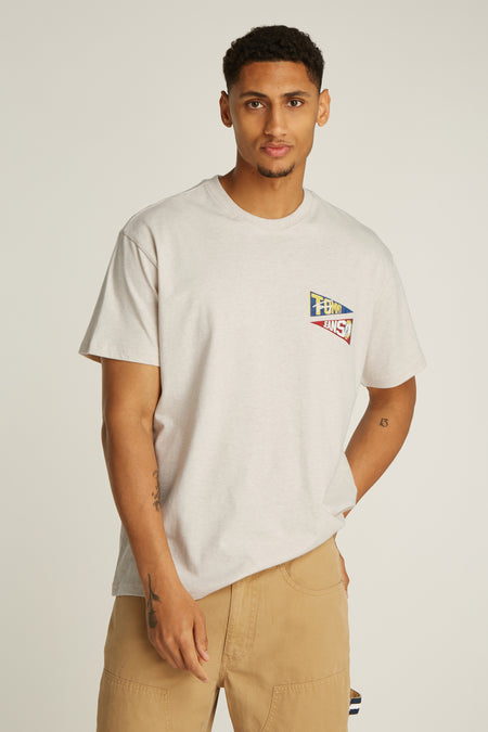 Ecru T-shirt met korte mouwen van TOMMY JEANS, met klein vlaglogo op de borst en model draagt kaki broek.
