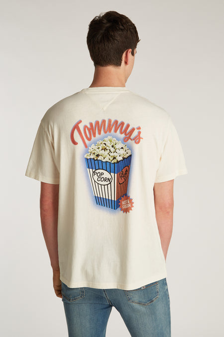 Wit T-shirt met korte mouwen van TOMMY JEANS, met popcorn-afbeelding op de rug en gedragen met een jeans.