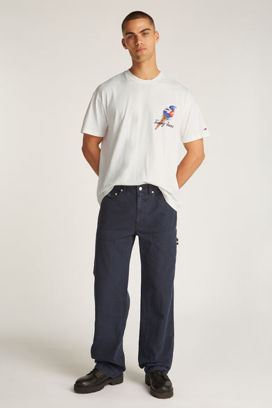 Wit T-shirt met korte mouwen van TOMMY JEANS, met een print van een ijsje, gecombineerd met een donkerblauwe broek en zwarte schoenen.
