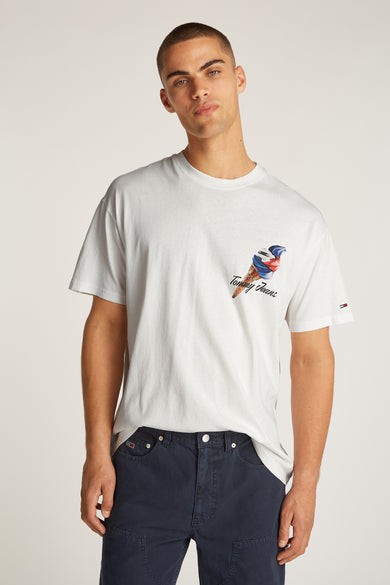 Wit T-shirt met korte mouwen van TOMMY JEANS, met een ijsmotief op de borst en gedragen met een donkerblauwe broek.
