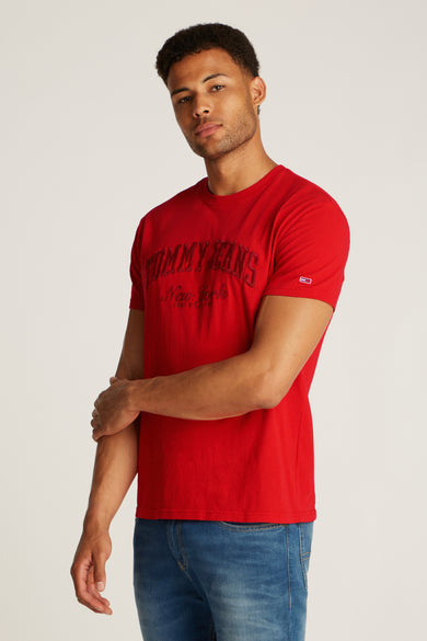 T-shirt rouge à manches courtes de TOMMY JEANS, avec une impression de logo et porté avec un jean bleu.