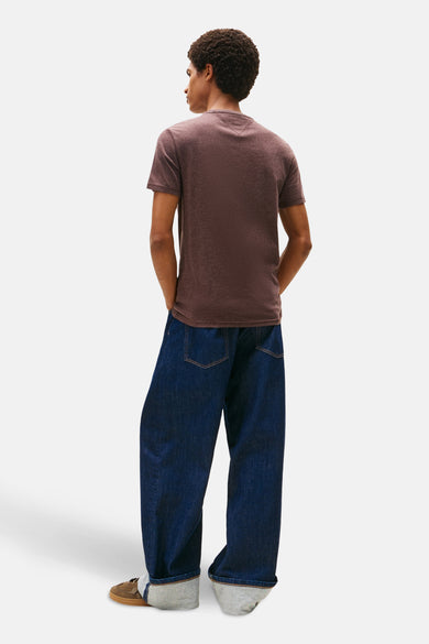 Bruin T-shirt met korte mouwen van TOMMY JEANS, met losse donkerblauwe jeans en bruine schoenen.