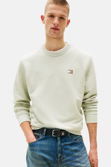 Sweater vert de TOMMY JEANS, avec des manches longues, associé à des jeans bleus et des chaussures vertes.