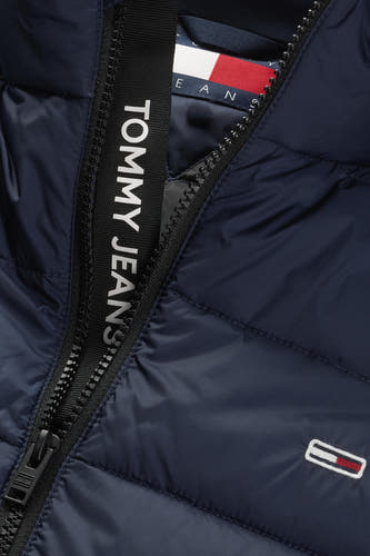 Blauwe bodywarmer van TOMMY JEANS, met logo-detail langs de rits en een klein merklogo op de borst.