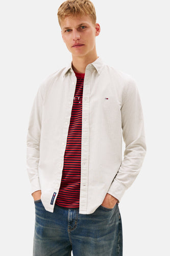 Man in gestreept overhemd en blauwe jeans.