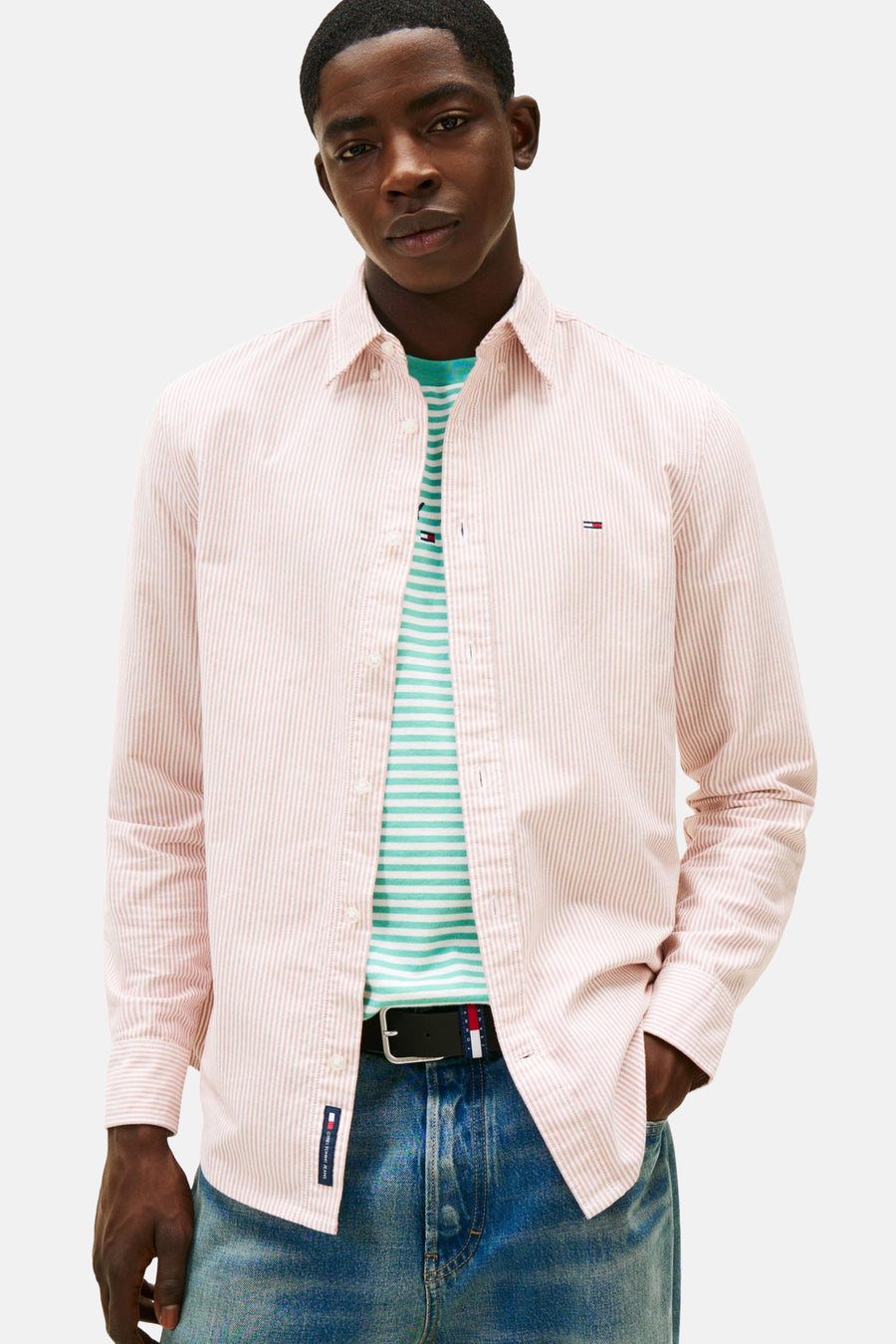 Man met roze gestreept overhemd en blauwe jeans.