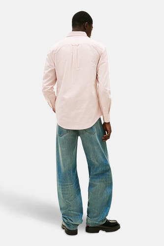 Rood gestreept overhemd met lange mouwen van TOMMY JEANS, losjes gedragen op een blauwe jeans en zwarte schoenen.
