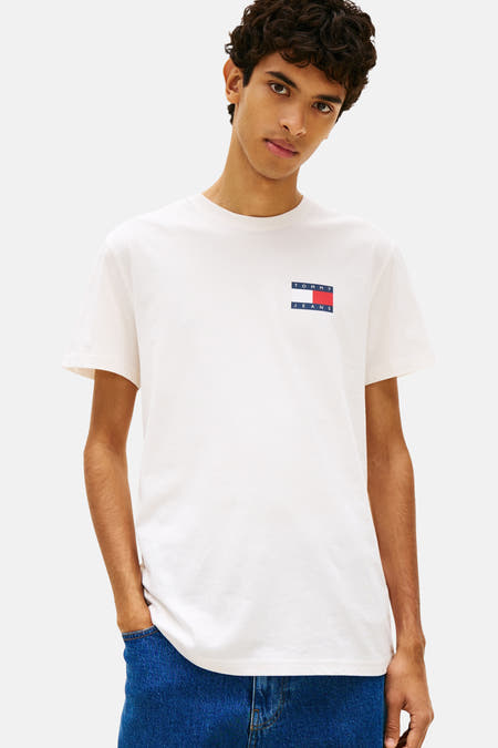 Wit T-shirt met korte mouwen van TOMMY JEANS, gedragen met jeans, en een klein logo op de borst.