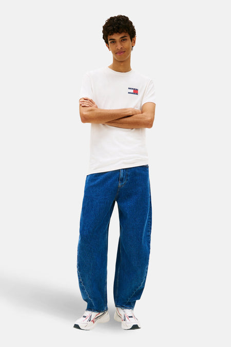 Wit T-shirt met korte mouwen van TOMMY JEANS, met logo op de borst, gecombineerd met wijde jeans en sneakers.
