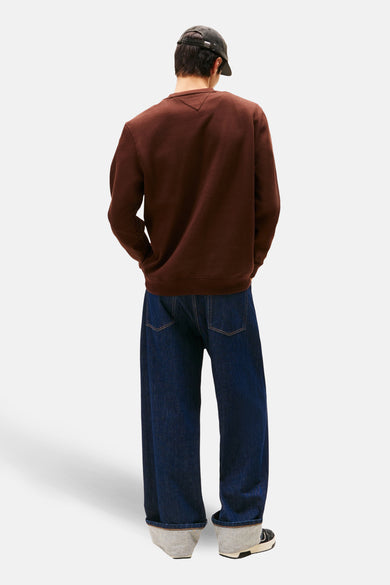 Bruine sweater van TOMMY JEANS, achterkant gezien, gecombineerd met een donkerblauwe jeans en een pet.