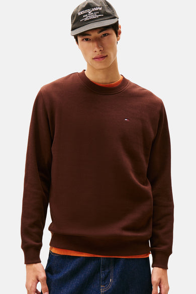 Bruine sweater van TOMMY JEANS, met een subtiel logo op de borst en een oranje shirt eronder.
