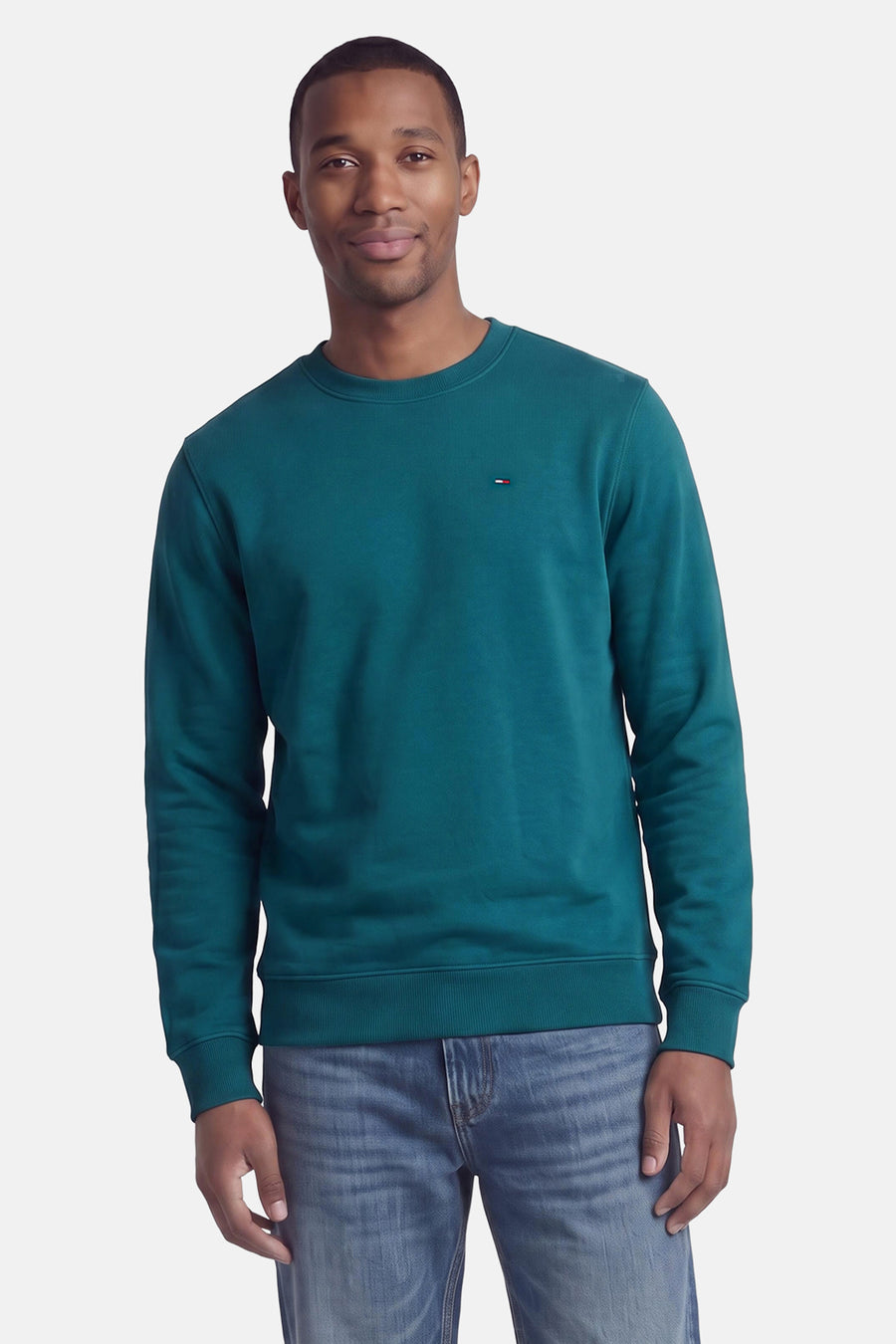 Groene ronde hals sweater van TOMMY JEANS, met klein logo op borst, gedragen met blauwe jeans, front view