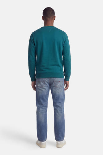 Groene ronde hals sweater van TOMMY JEANS, achterzijde, met ribboorden en casual fit, gedragen met blauwe jeans en witte sneakers