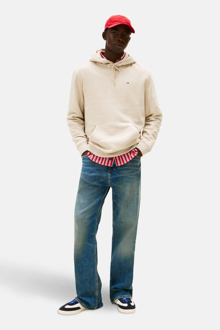 Gilet beige avec capuche de Tommy Jeans, avec un bonnet rouge et une chemise à carreaux rouge.