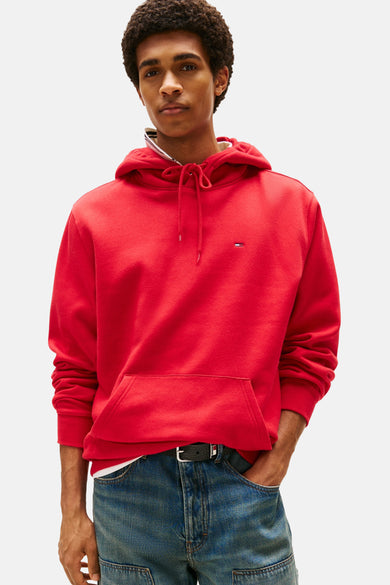 Pull-over rouge Tommy Tommy Jeans avec un capuchon, une coupe décontractée et porté avec des jeans bleus.