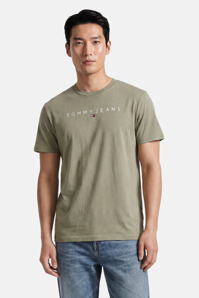 Olijfgroene korte mouw T-shirt van TOMMY JEANS met wit logo en klein vlaggetje, gedragen door model in jeans, front view
