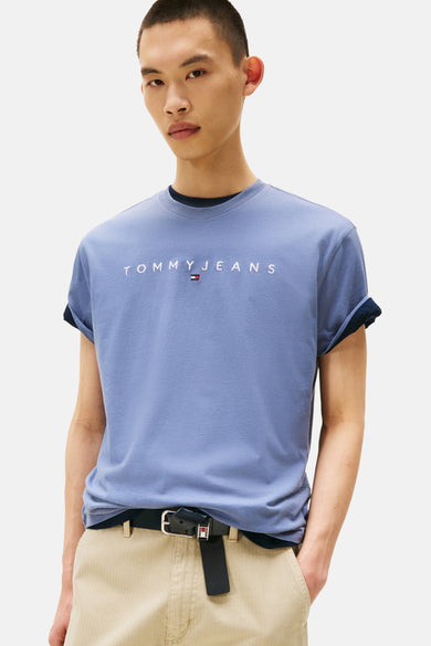Blauw T-shirt met korte mouwen van TOMMY JEANS, met opgerolde mouwen en een logo op de borst, gecombineerd met een bruine broek en zwarte riem.
