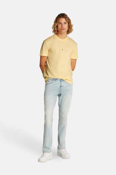 T-shirt jaune à manches courtes de TOMMY JEANS, porté avec des jeans légers et des baskets blanches.
