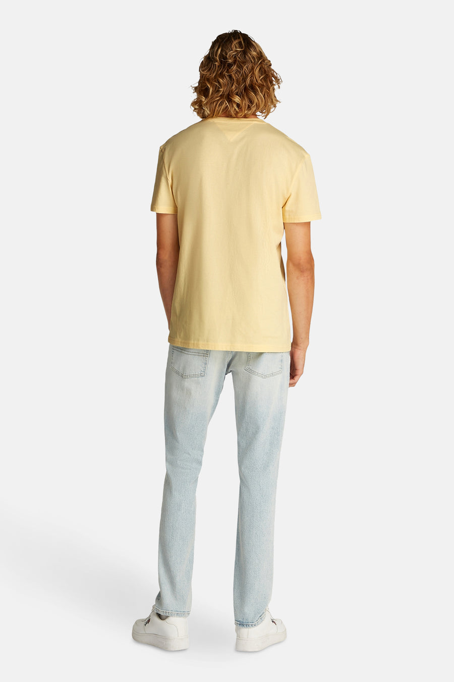 Geel T-shirt met korte mouwen van TOMMY JEANS, met een jeansbroek en witte sneakers.