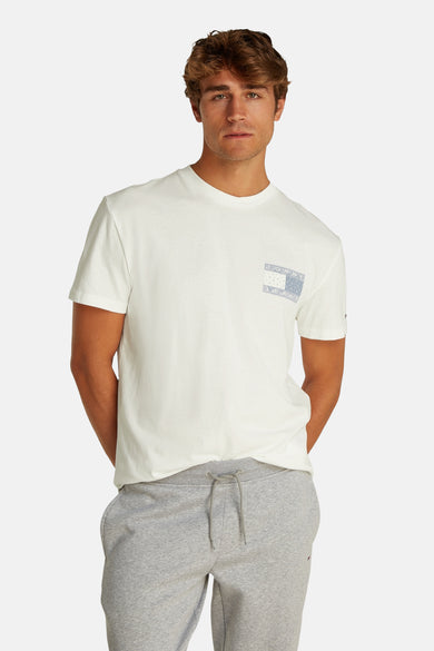 Wit T-shirt met korte mouwen van Tommy Jeans, met een klein blauw logo op de borst en gedragen met een grijze joggingbroek.