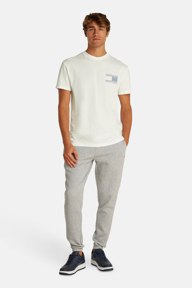 Wit T-shirt met korte mouwen van TOMMY JEANS, met een subtiel logo detail op de borst, gecombineerd met grijze joggingbroek en donkerblauwe sneakers.