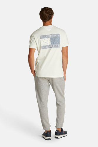 Man van achteren in T-shirt, grijze joggingbroek en blauwe sneakers.