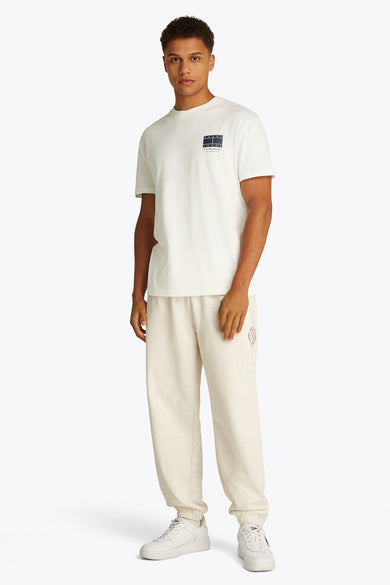 Wit T-shirt met korte mouwen van TOMMY JEANS, met klein logo op de borst, gedragen met een joggingbroek en witte sneakers.