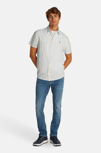Blauw gestreept overhemd met korte mouwen van TOMMY JEANS, gedragen met jeans en blauwe sneakers.