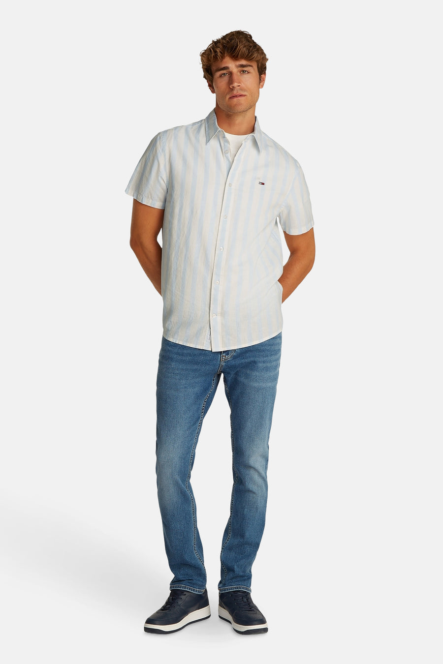 Blauw gestreept overhemd met korte mouwen van TOMMY JEANS, gedragen met jeans en blauwe sneakers.
