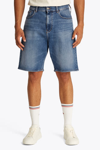 Jeansshort van blauw denim van TOMMY JEANS, gedragen met witte sokken met strepen en crèmekleurige sneakers.