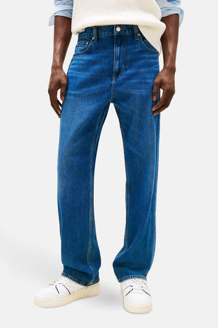Jeans straight van donkerblauw denim van TOMMY JEANS, gedragen met een gebreide trui en witte sneakers.