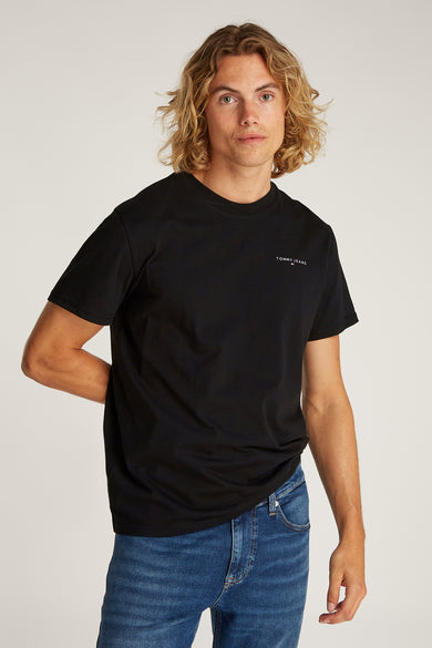 Zwart T-shirt met korte mouwen van TOMMY JEANS, gedragen met een blauwe jeansbroek.
