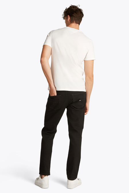 Wit T-shirt met korte mouwen van TOMMY JEANS, achterkant gezien met een hand in de broekzak.