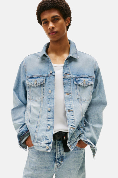 Jeansjas van lichtblauw denim van TOMMY JEANS, met knoopsluiting en opgestikte zakken, gedragen over een wit hemd.
