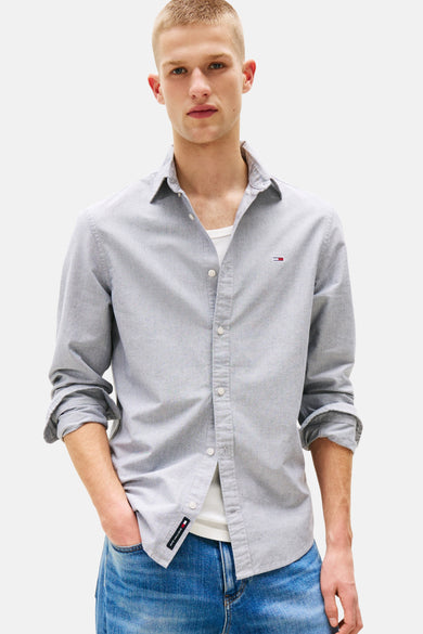 Blauw overhemd met lange mouwen van TOMMY JEANS, met knoopsluiting en opgerolde mouwen gedragen over een wit T-shirt.