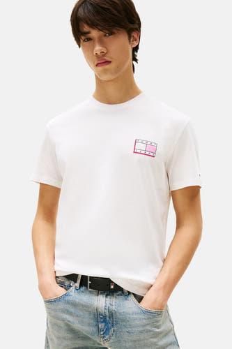 T-shirt écru à manches courtes de Tommy Jeans, avec un logo rose sur la poitrine et porté avec un pantalon en denim.