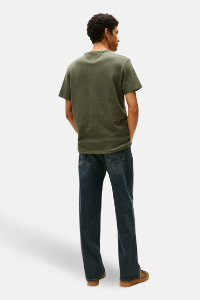 Groen T-shirt met korte mouwen van TOMMY JEANS, met textuur, gecombineerd met donkere jeans en bruine schoenen, gezien van achteren.