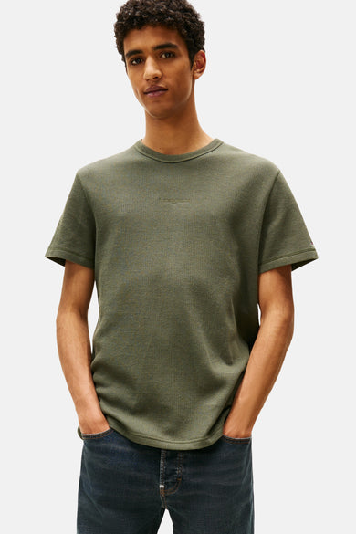 Groen T-shirt met korte mouwen van TOMMY JEANS, met een subtiele textuur en gedragen met donkere jeans.

