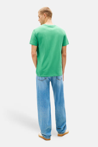 Groen T-shirt met korte mouwen van TOMMY JEANS, met een effen design en gedragen met wijde jeans en sneakers.
