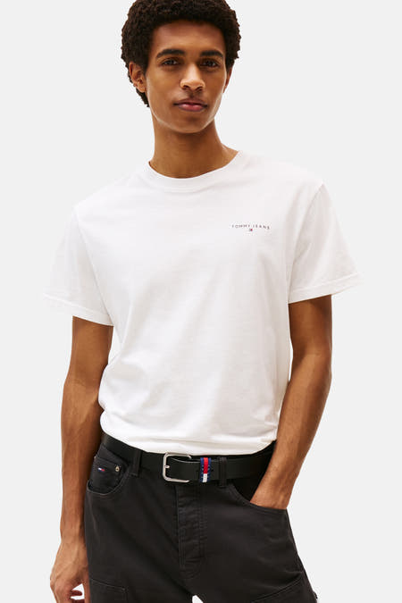 Wit T-shirt met korte mouwen van TOMMY JEANS, gedragen met een zwarte broek en riem.