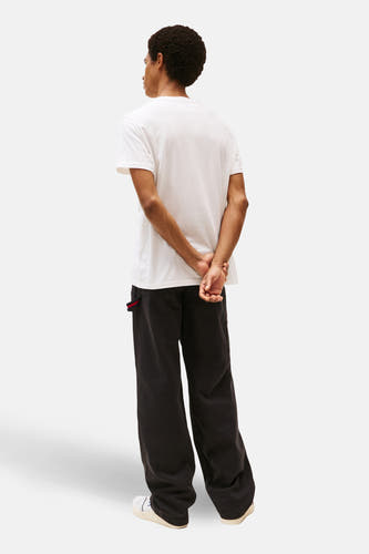 Wit T-shirt met korte mouwen van TOMMY JEANS, met de rug naar de camera gericht, gecombineerd met een zwarte broek.