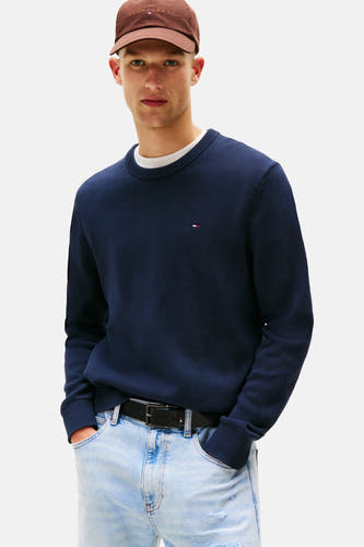 T-shirt bleu avec col rond de TOMMY JEANS, porté avec des jeans bleus clairs et un chapeau marron.