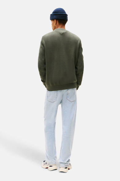 T-shirt vert avec col rond de TOMMY JEANS, associé à des jeans bleu clair et des baskets crème.