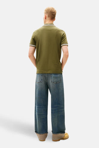 Kaki polo met korte mouwen van TOMMY JEANS, met witte details aan de kraag en mouwen, gezien vanaf de achterkant.
