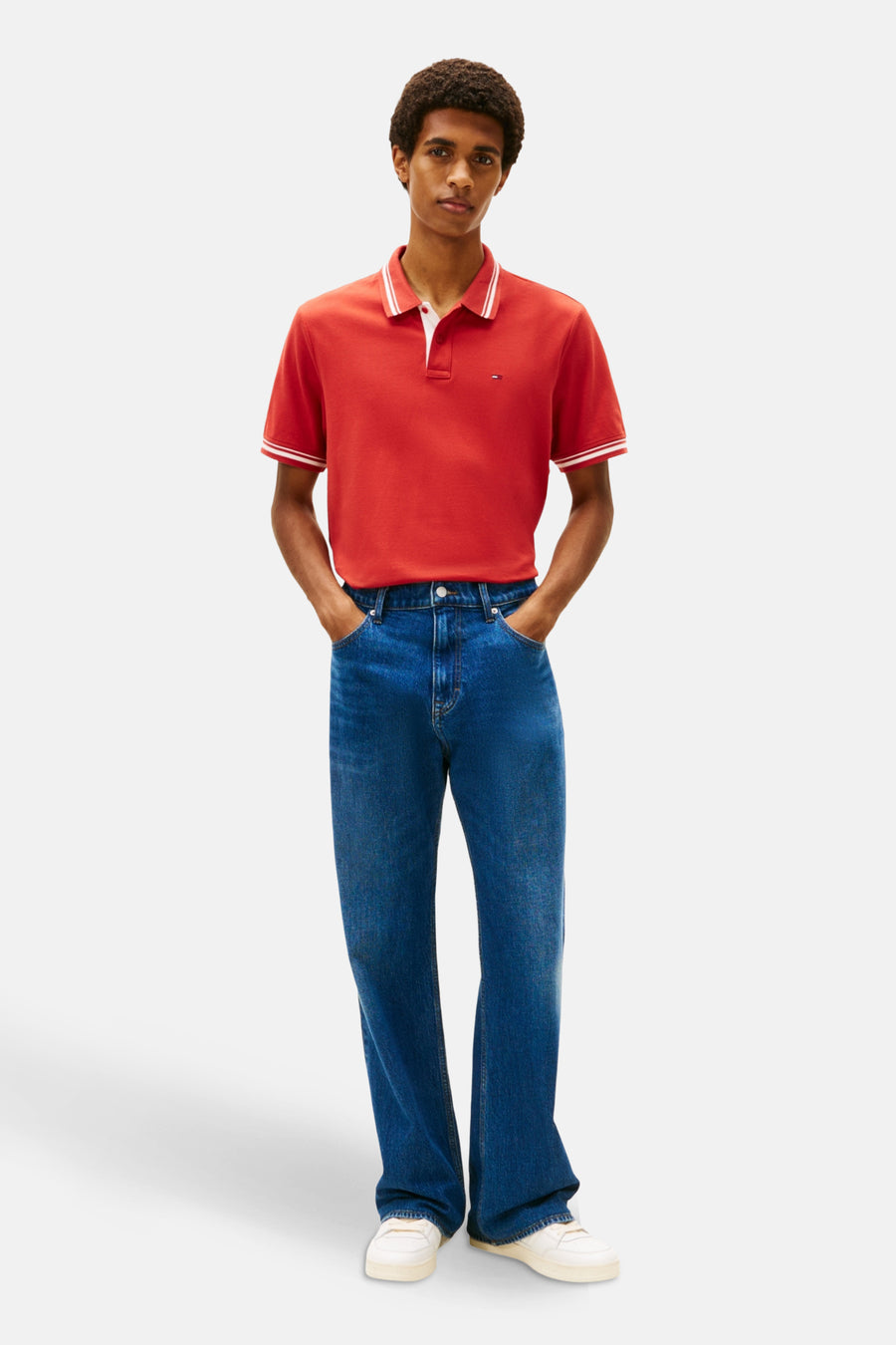 Man in rood poloshirt en blauwe jeans.