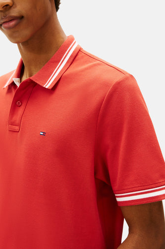 Close-up rode poloshirt met wit gestreepte kraag en mouwen.